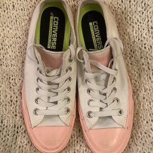 Women’s Converse white low rise sneakers with pink
toecaps and accents, size 8.